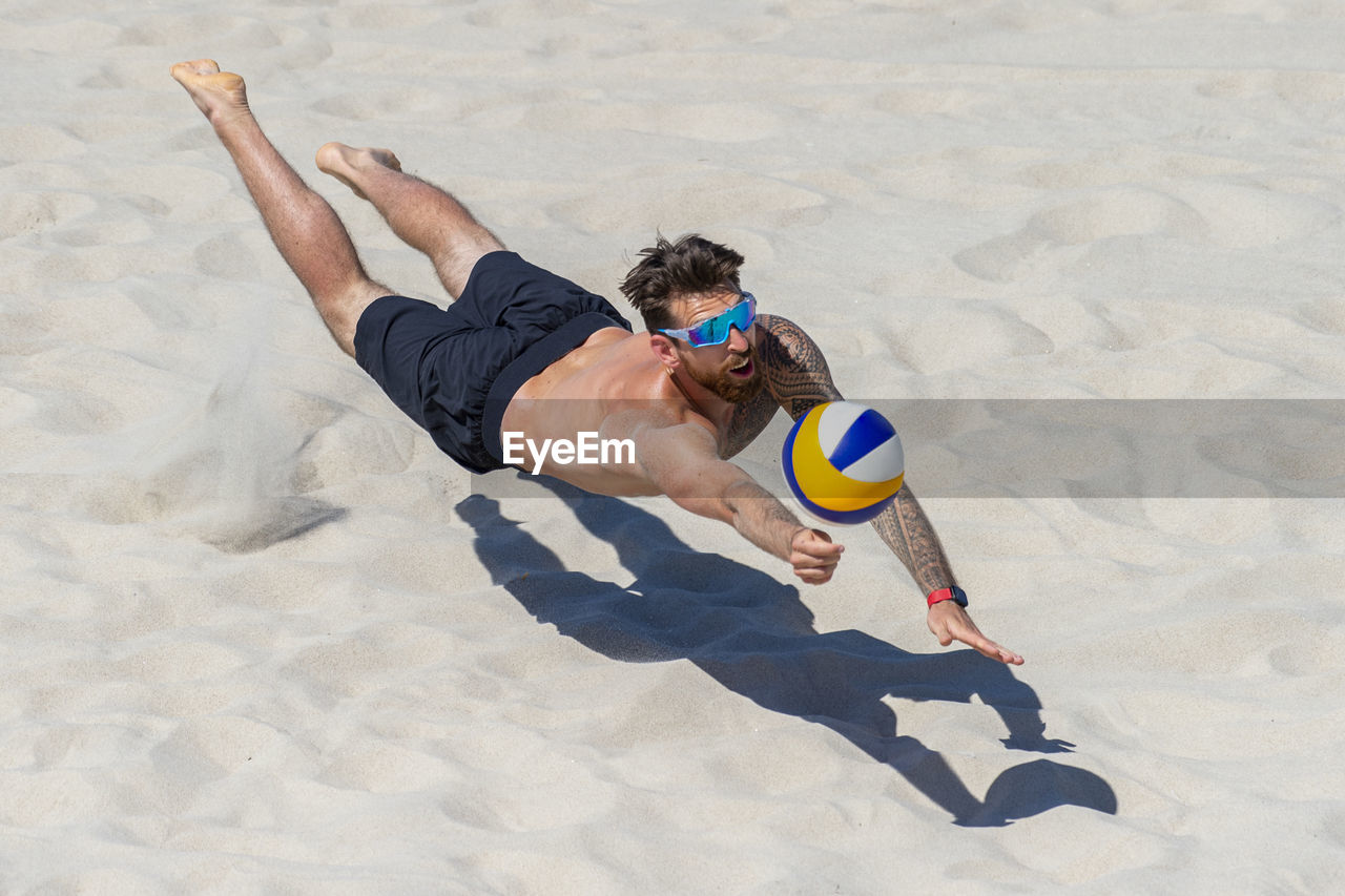 HIGH ANGLE VIEW OF PERSON PLAYING SOCCER ON SAND
