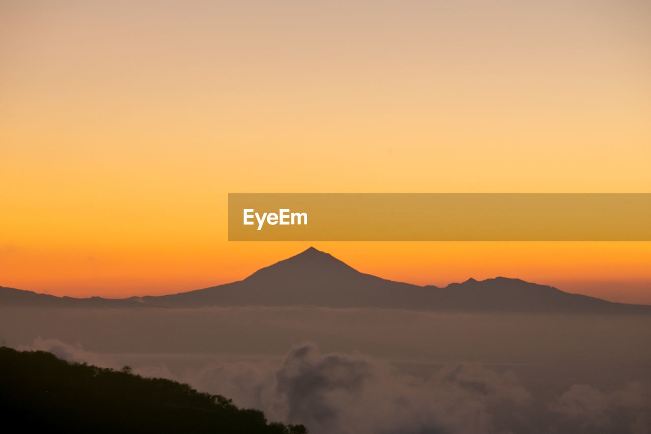 Scenic view of silhouette mountains against sky during sunset