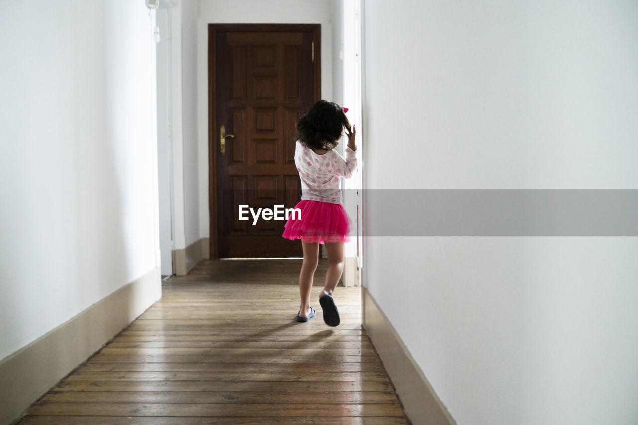 Rear view of girl walking on floor at home