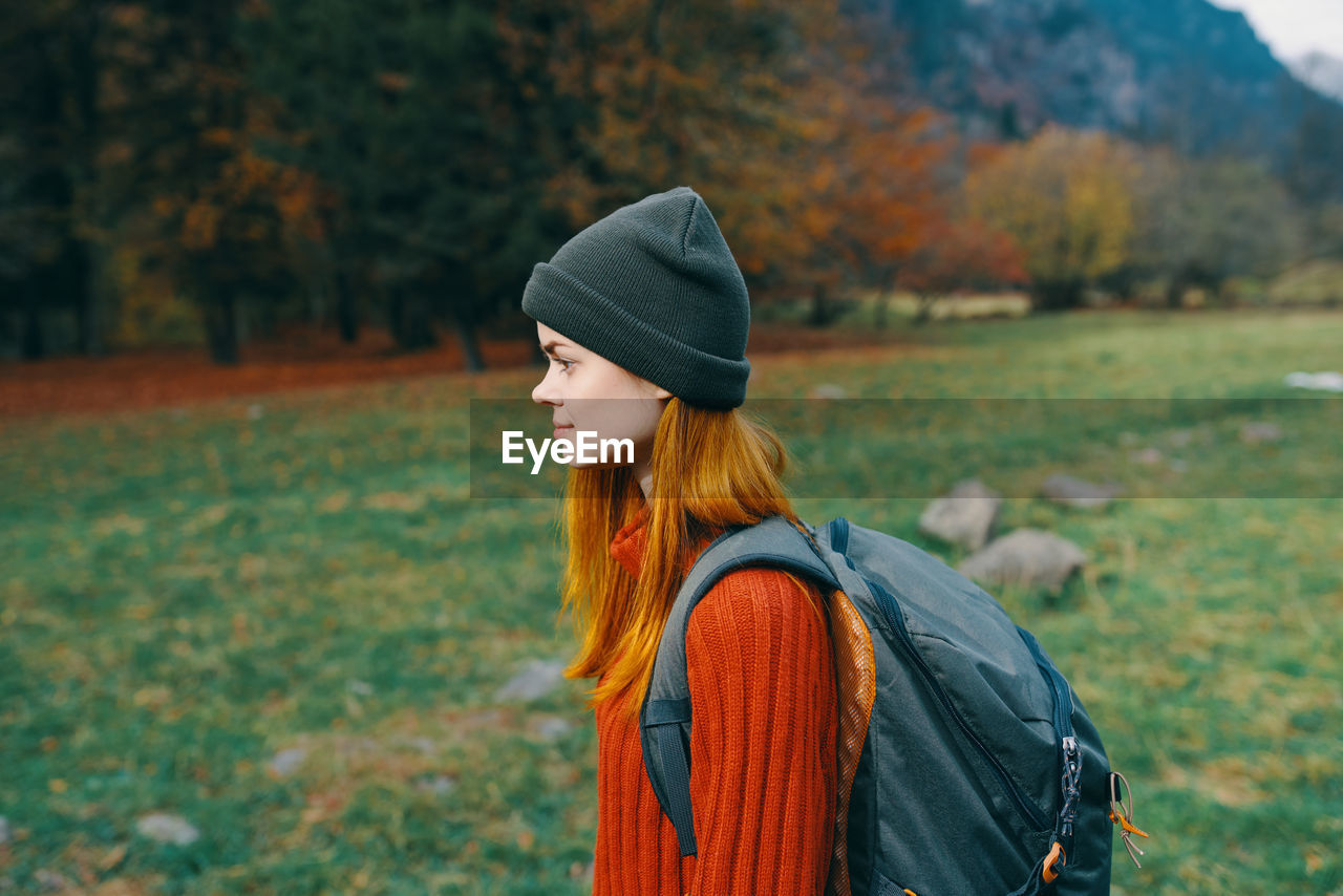 FULL LENGTH OF YOUNG WOMAN STANDING IN PARK