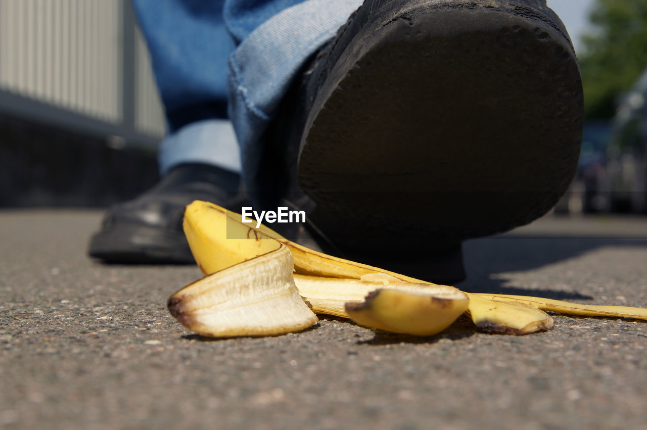 Low section of person over banana peel on footpath