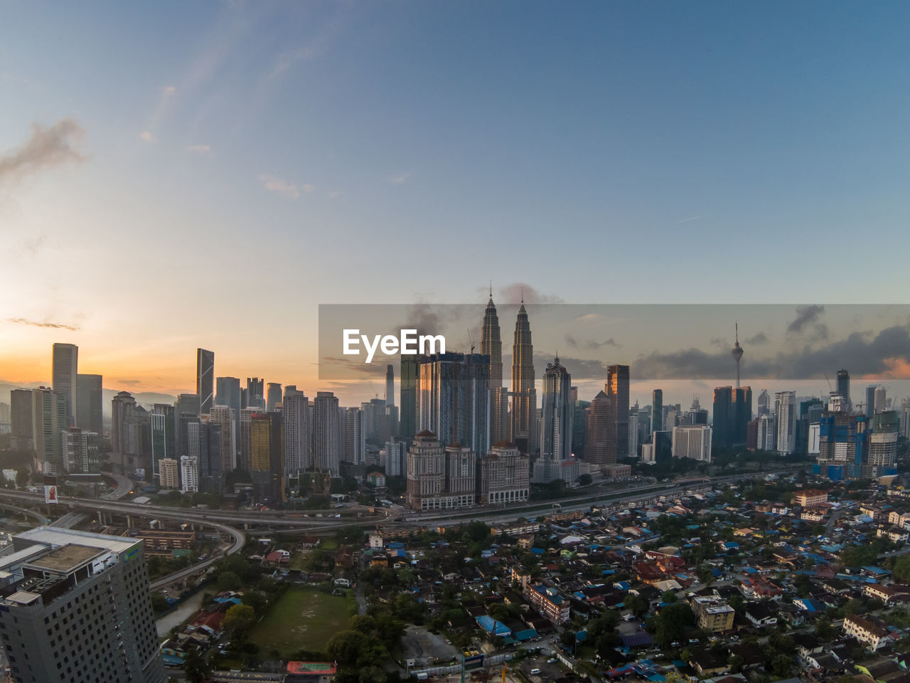 Modern buildings in city against sky during sunset