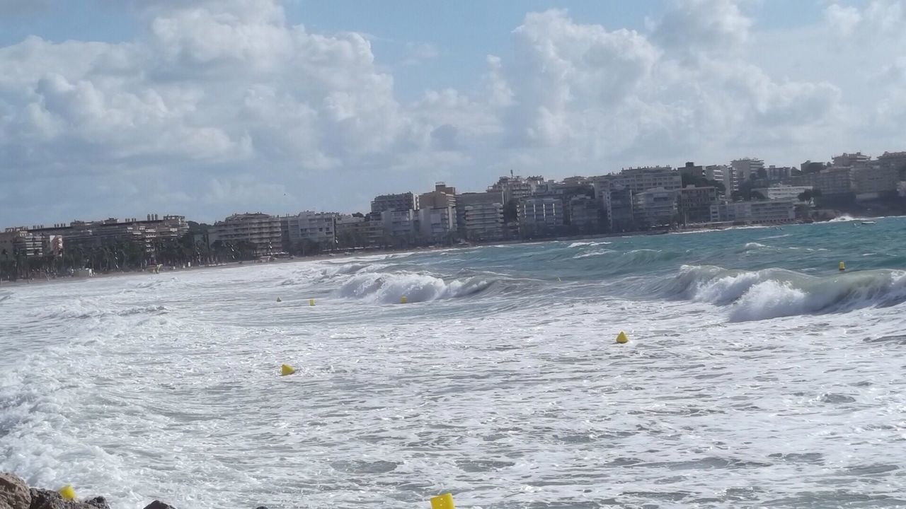 Waves in sea with city in background