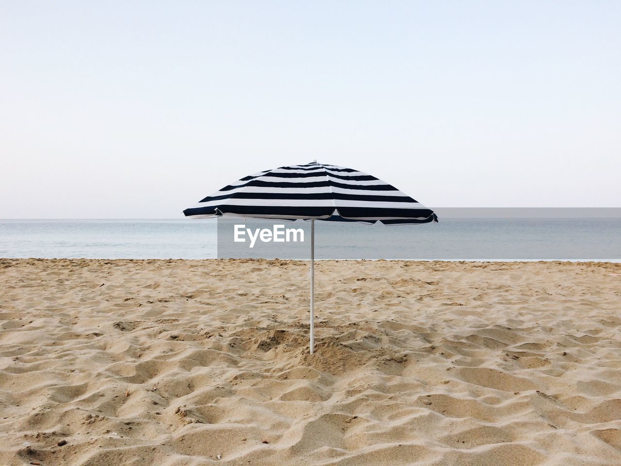 Sun umbrella on beach against clear sky