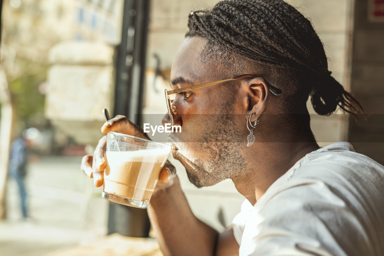 PORTRAIT OF YOUNG MAN DRINKING WATER FROM GLASS