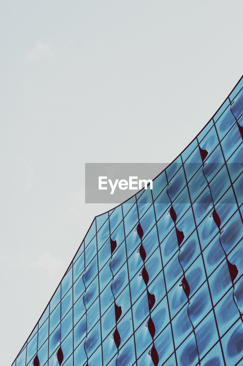 LOW ANGLE VIEW OF GLASS BUILDING AGAINST CLEAR SKY