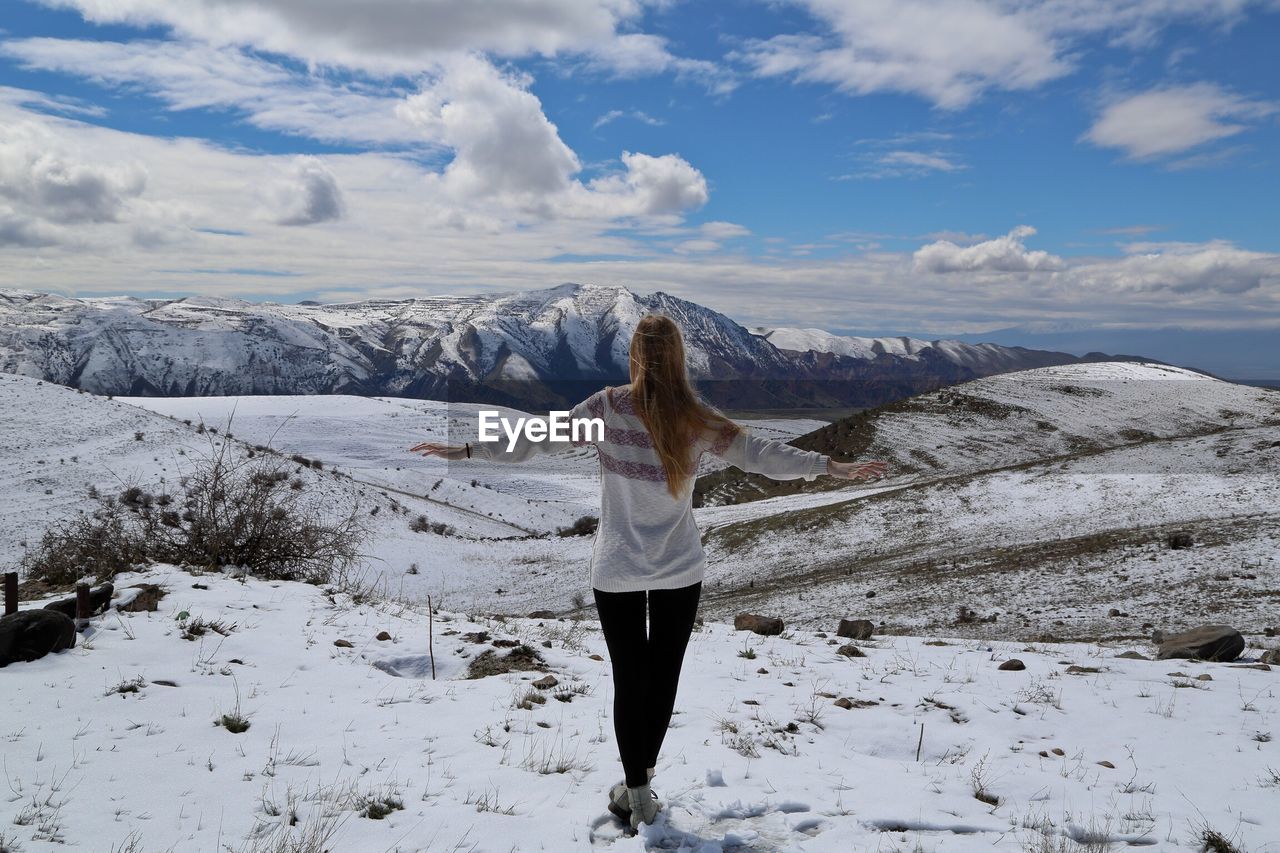 Rear view of woman standing on snow covered mountain