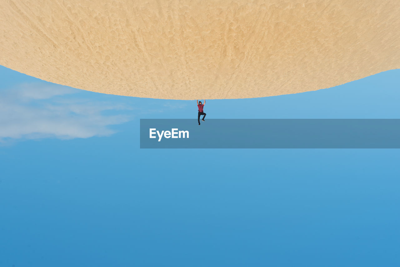 Upside down image of man doing handstand at desert