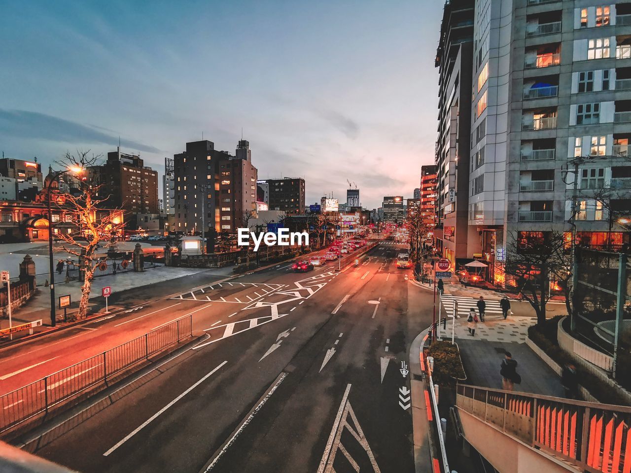 Light trails on city street amidst buildings against sky