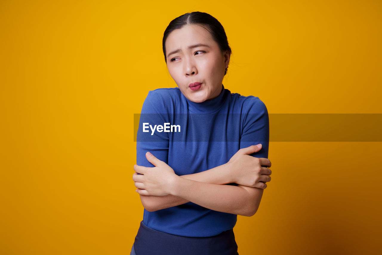 MAN STANDING AGAINST YELLOW BACKGROUND