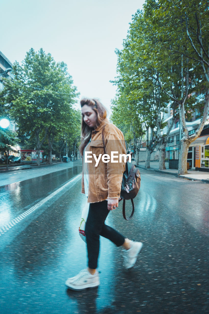 WOMAN WALKING ON ROAD IN CITY