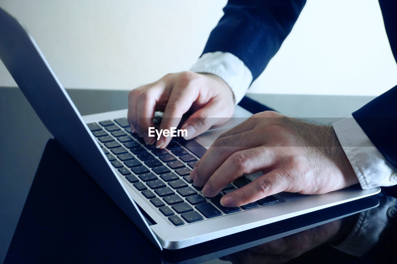 MIDSECTION OF MAN USING MOBILE PHONE