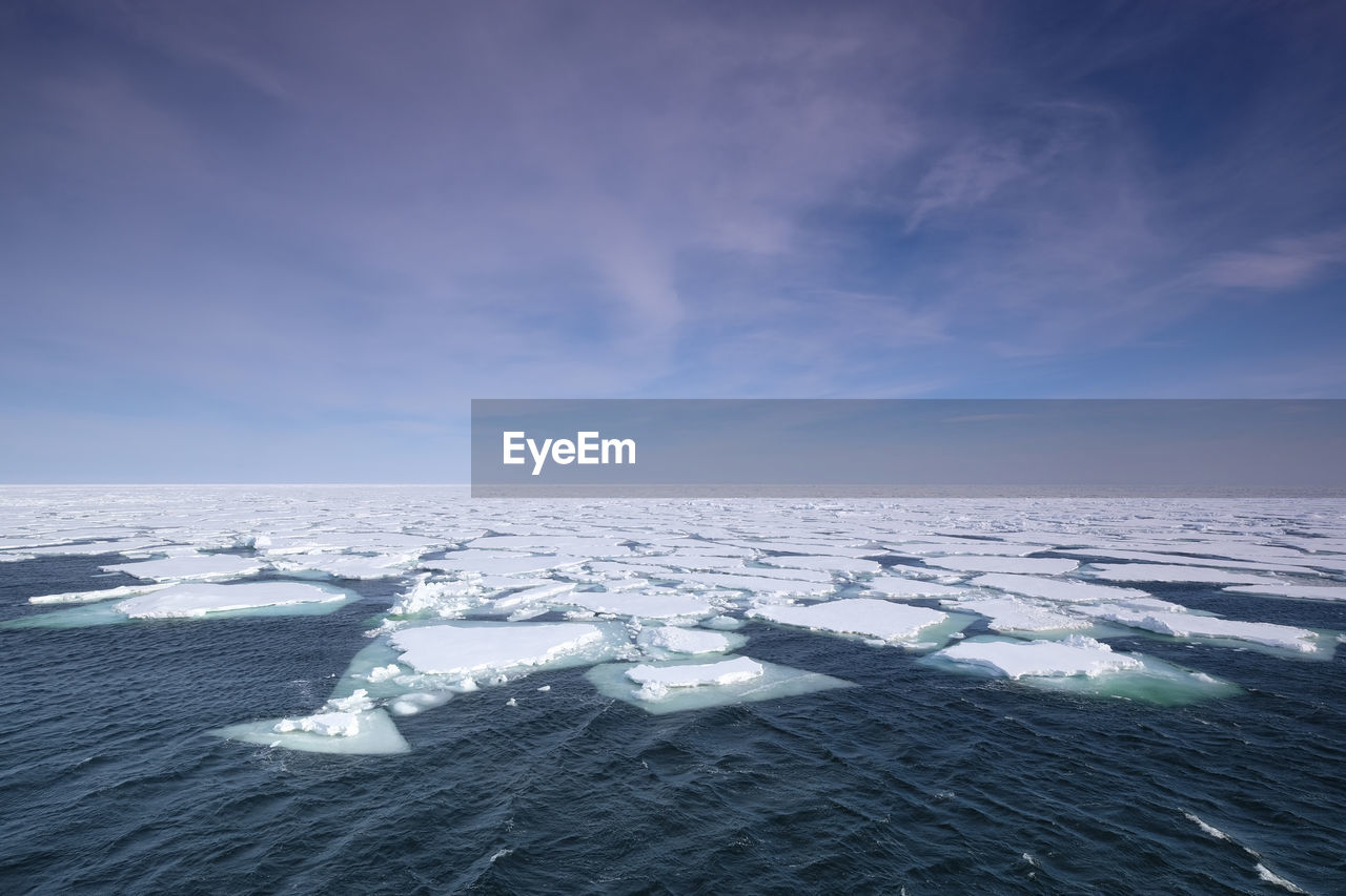 Floating pack ice in the arctic ocean with dramatic sky at a sunny clear day