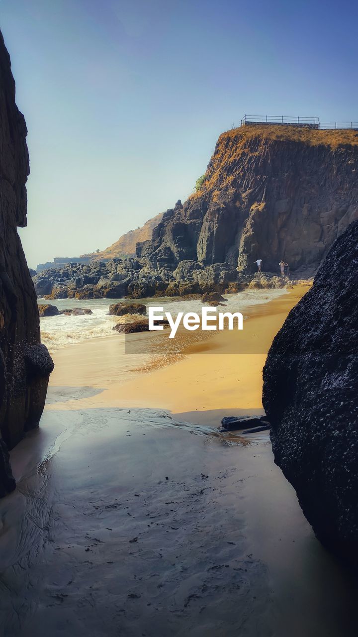 ROCK FORMATIONS ON SHORE AGAINST CLEAR SKY