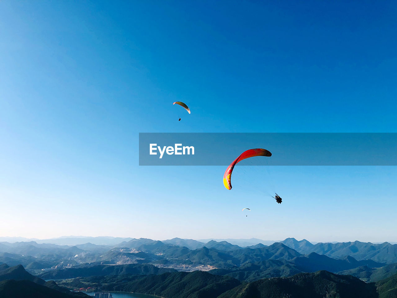 Kite flying over mountain against blue sky