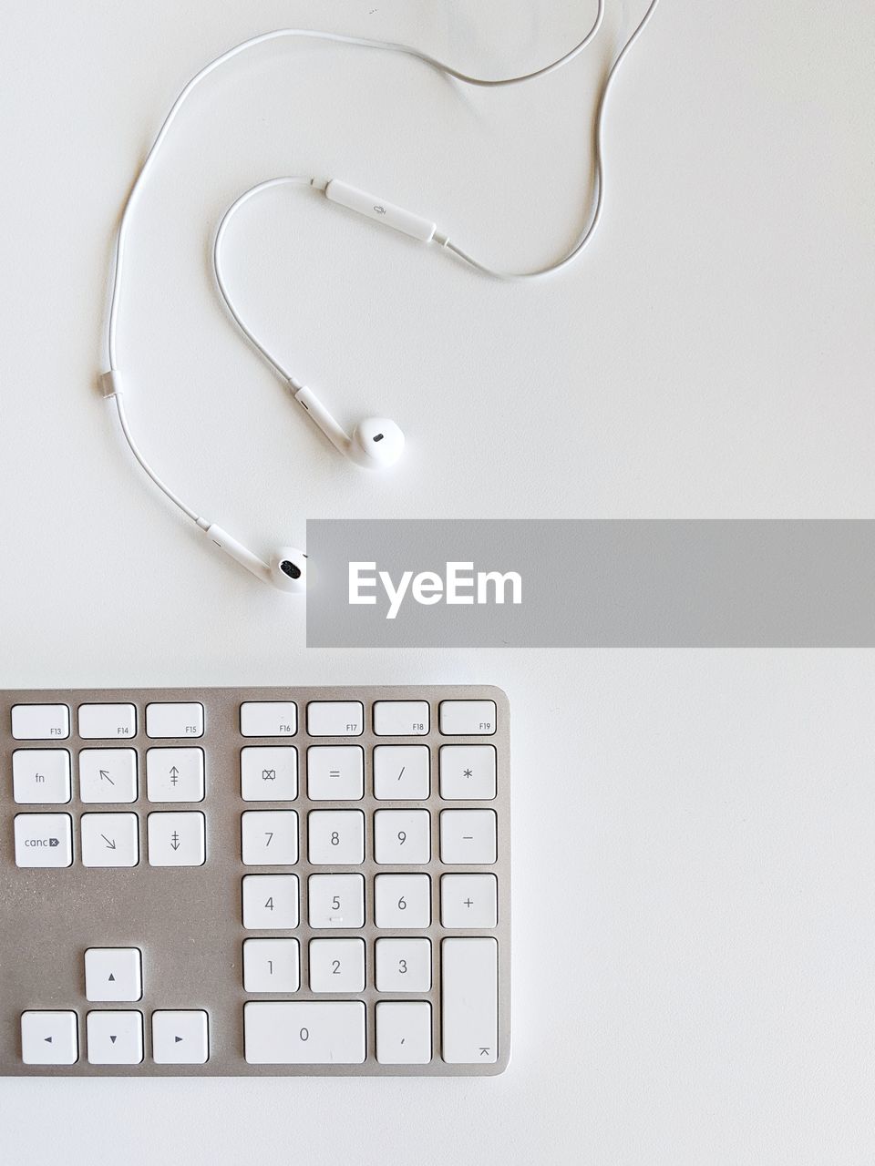 Close-up of computer keyboard and earbuds on table