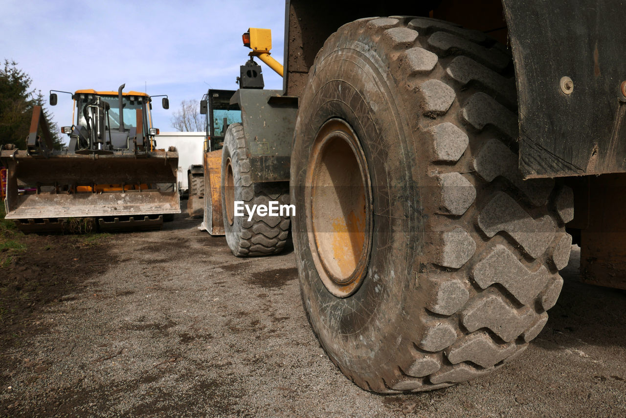Earth movers on field against sky