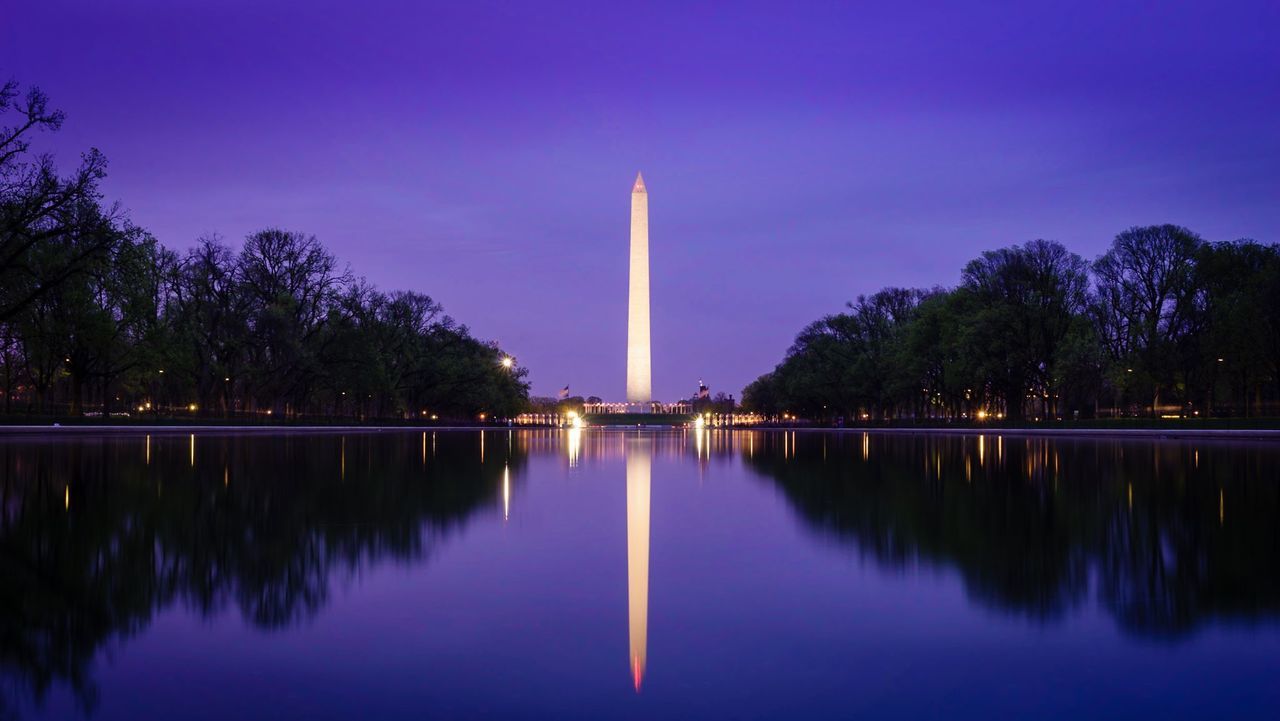 Reflection of illuminated washington monument on lake against sky during dusk