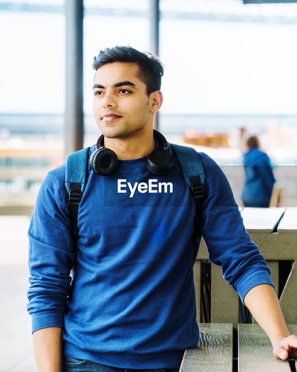 Young man looking away while standing against railing