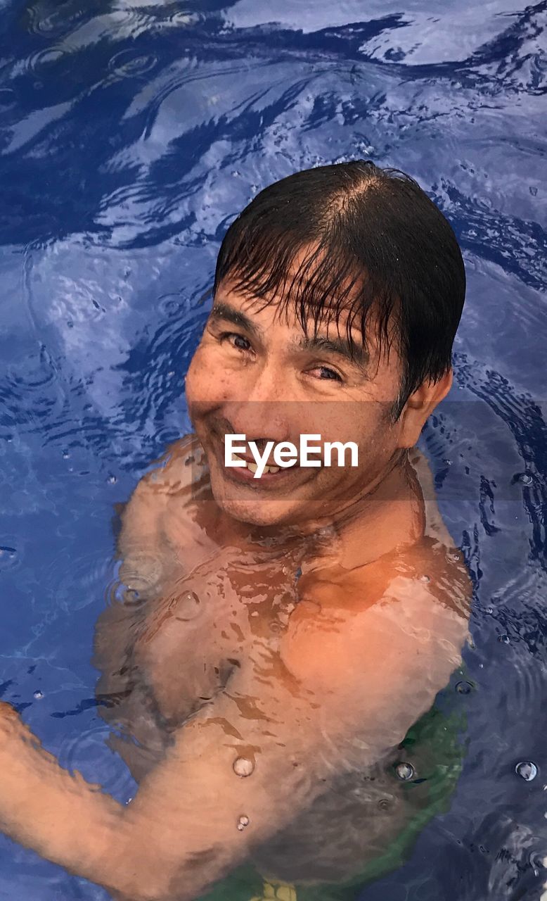 High angle portrait of smiling man swimming in pool