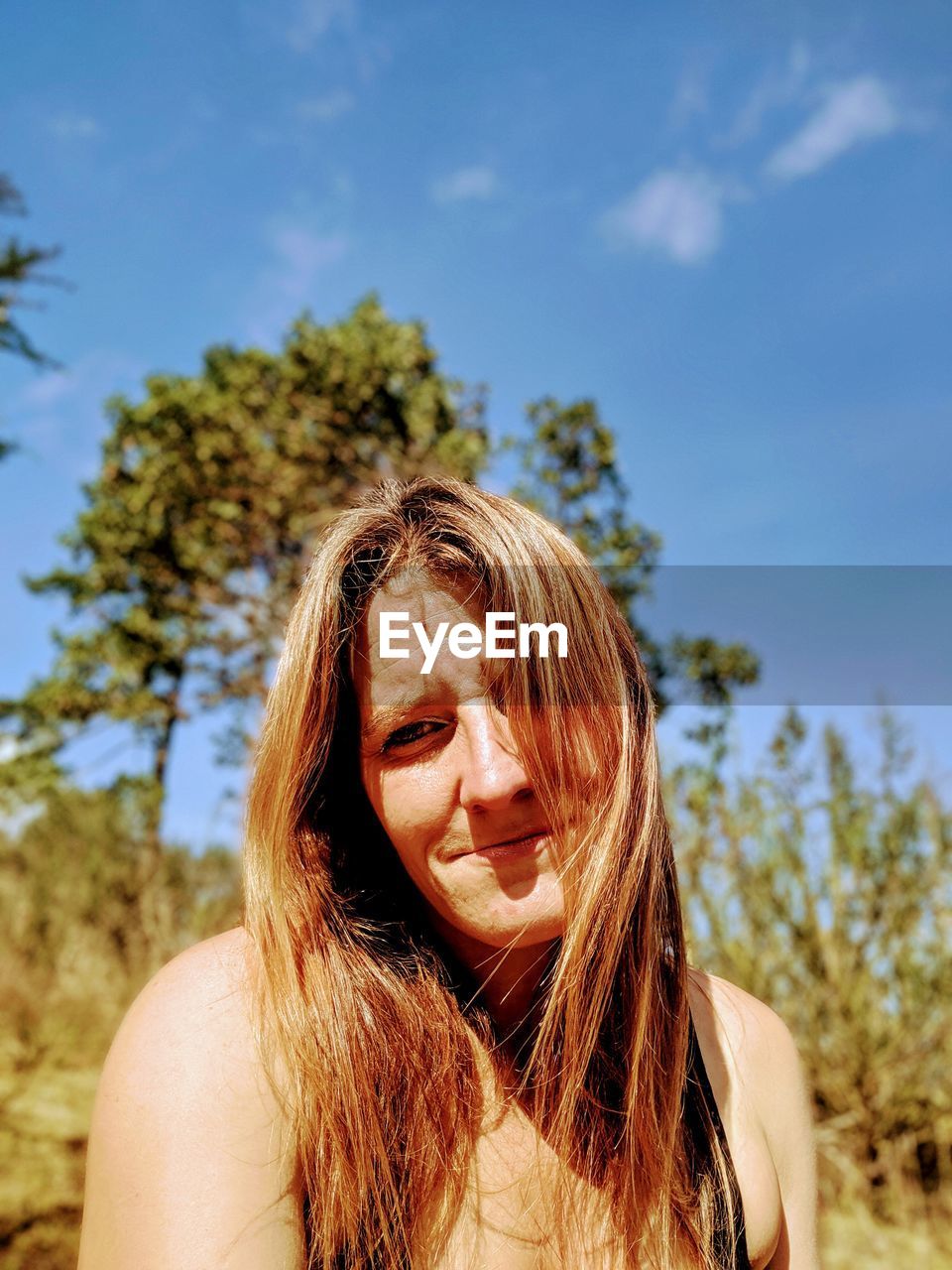 Portrait of woman with brown hair standing against sky