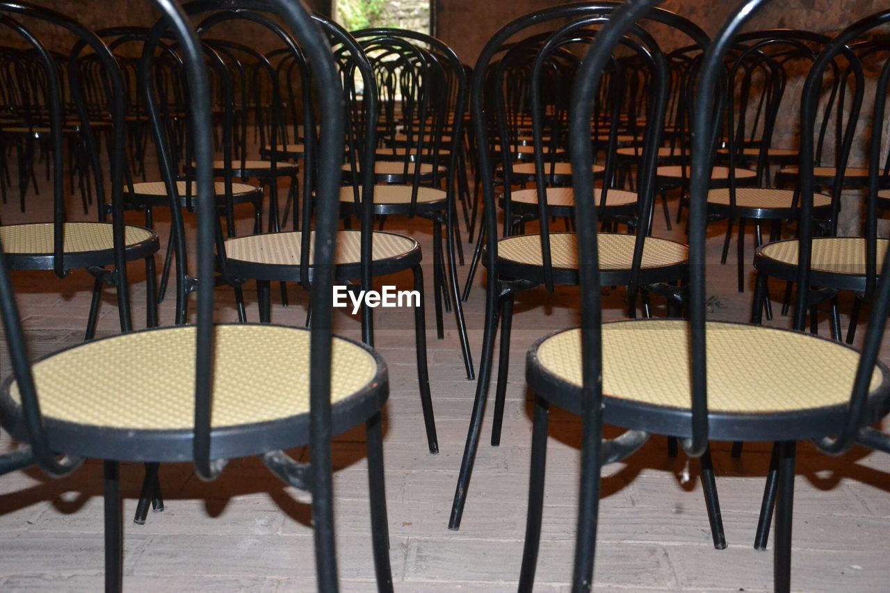 EMPTY CHAIRS AND TABLES ARRANGED IN ROW ON WOODEN TABLE