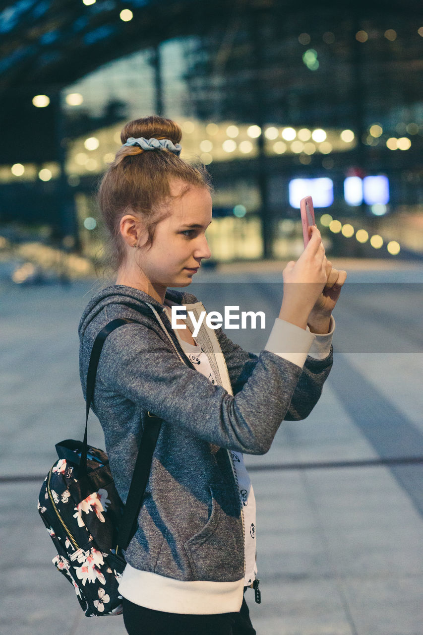 Woman photographing on smart phone while standing in airport