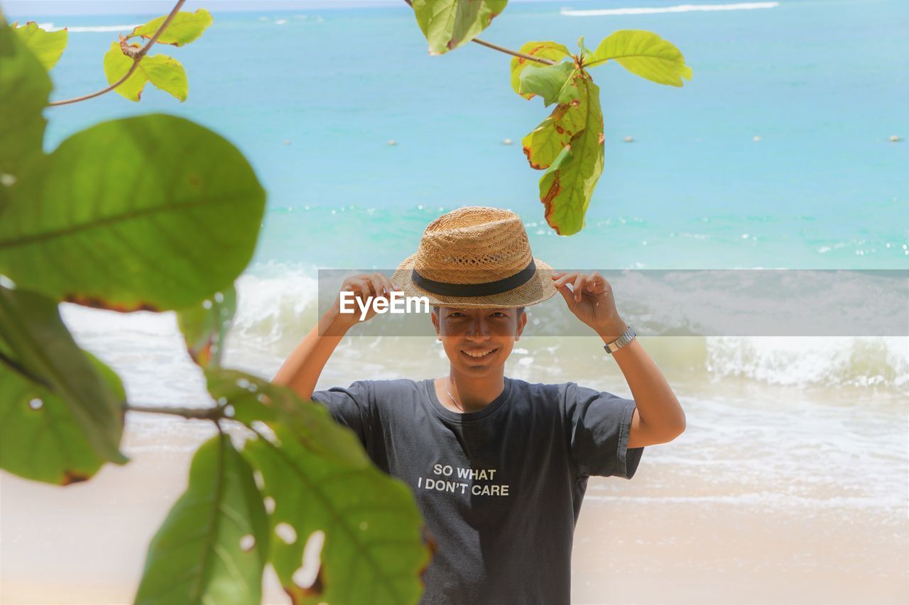 Portrait of man seen through leaves at beach