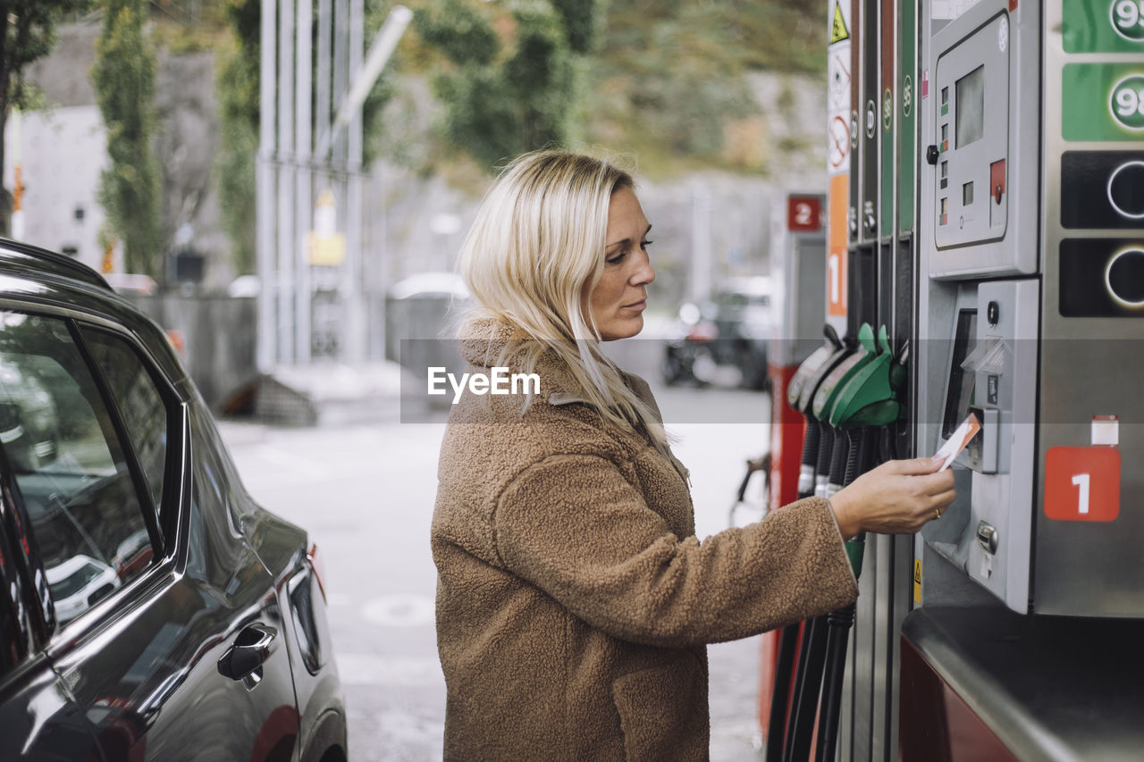 Mature woman doing payment via credit card at fuel station