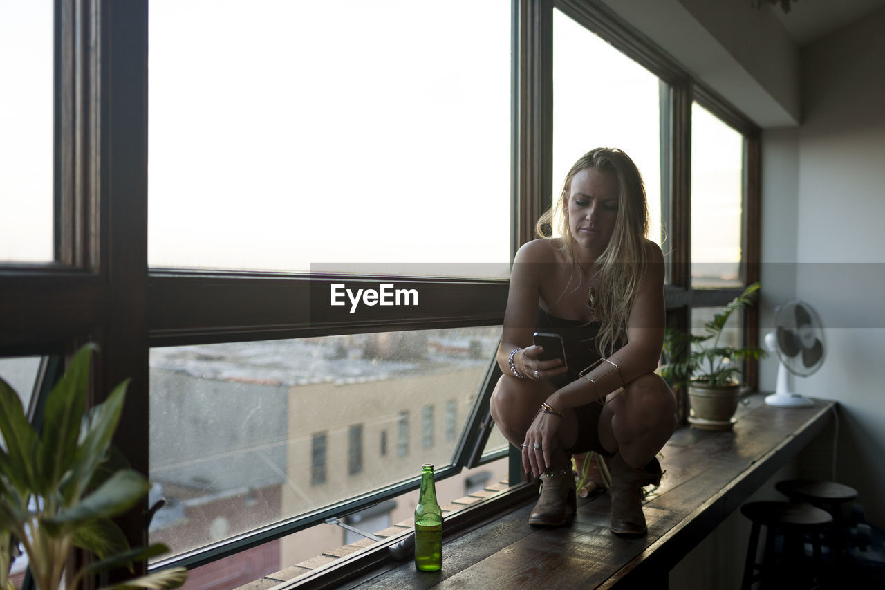 Young woman crouching on a window sill