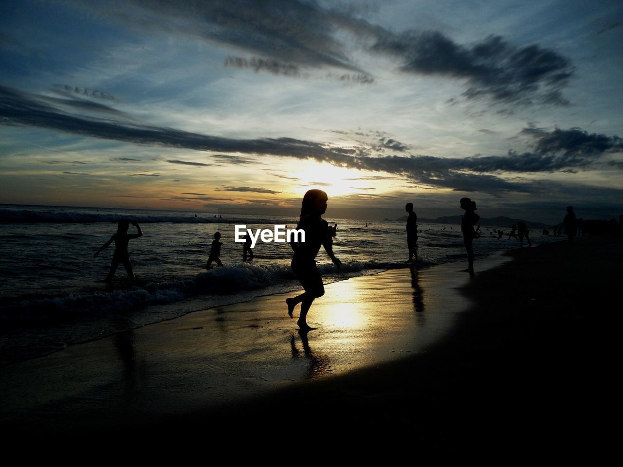 People relaxing on beach at sunset