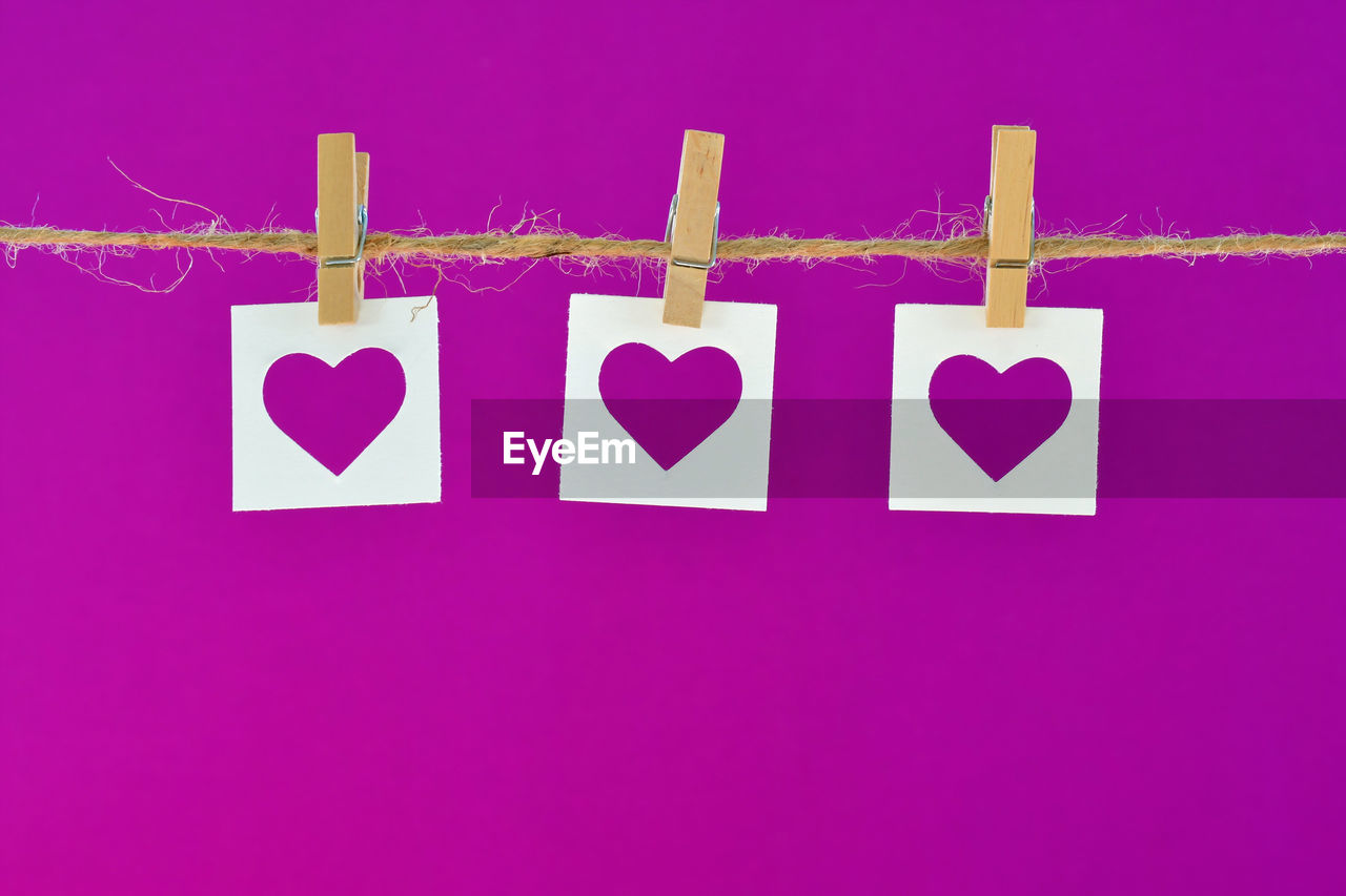 Close-up of heart shapes hanging on purple background