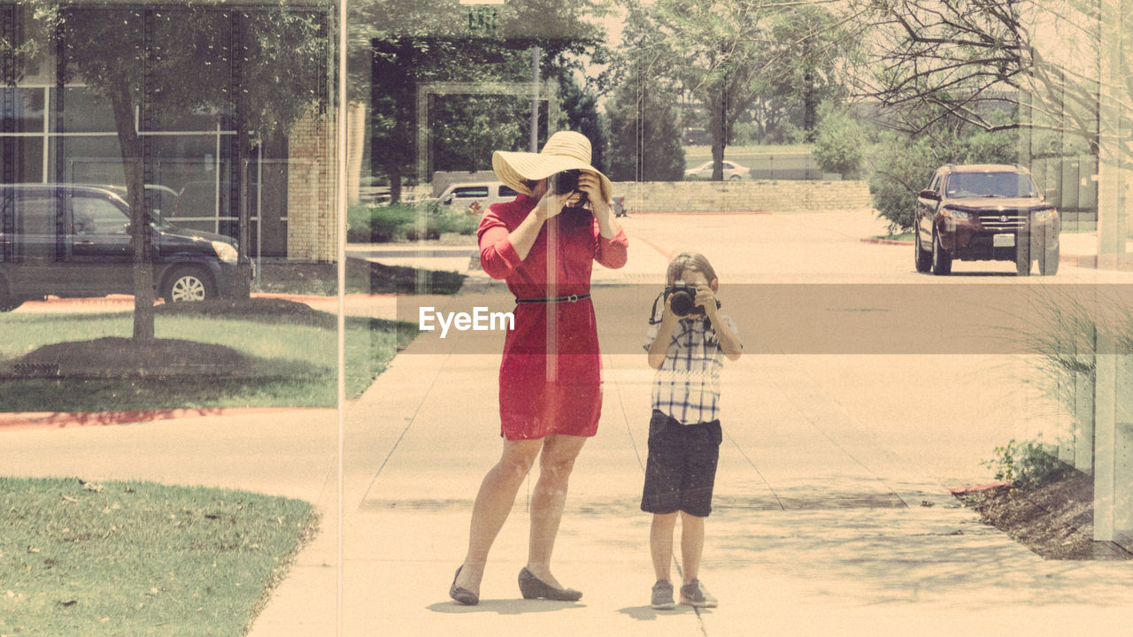 Reflection of mother and son photographing on glass