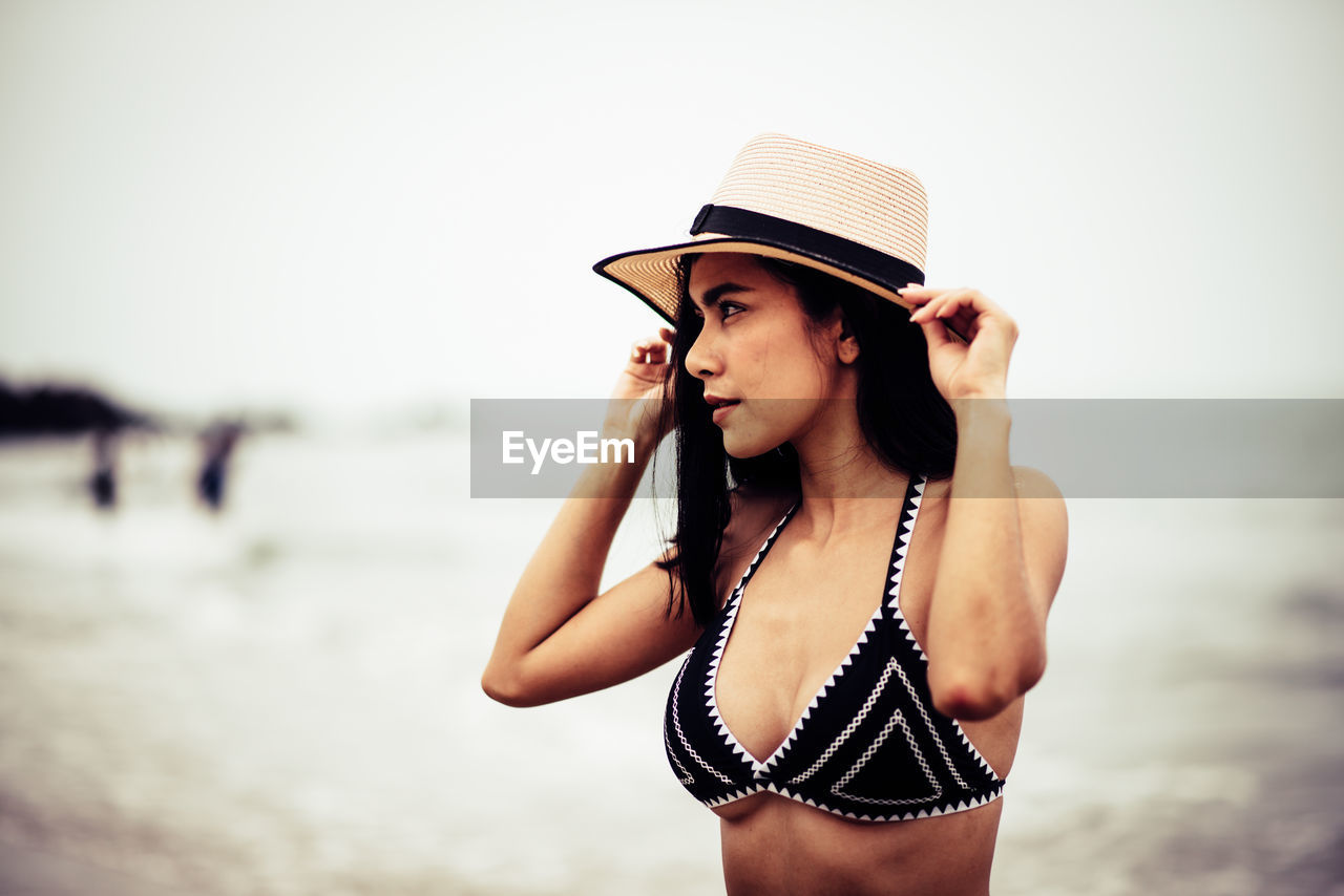 Woman looking away while standing at beach