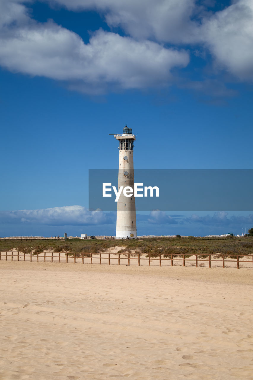 architecture, guidance, sky, lighthouse, built structure, tower, security, land, beach, building exterior, protection, building, sea, cloud, sand, water, nature, coast, travel destinations, travel, environment, blue, coastline, day, sand dune, no people, ocean, landscape, scenics - nature, outdoors, tourism, horizon, water's edge, history, observation tower, the past, non-urban scene, shore