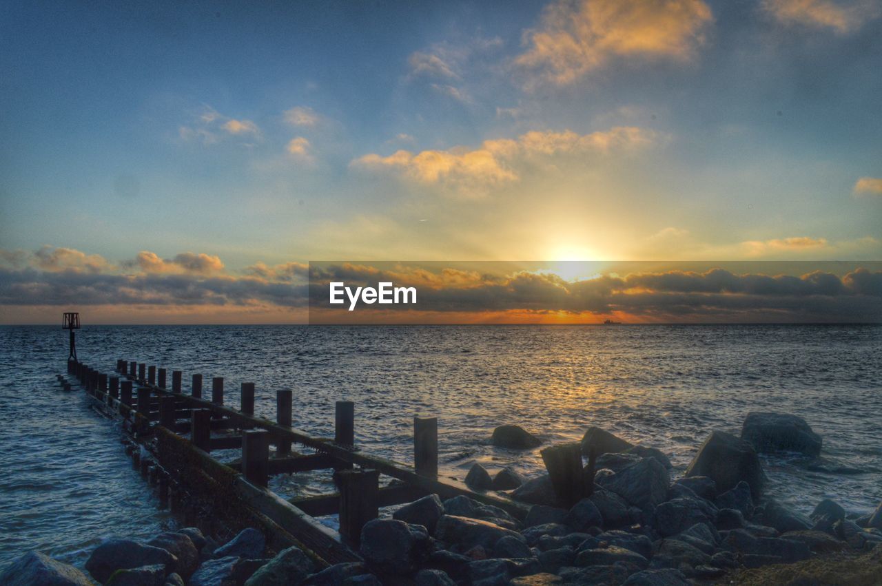 Groyne in sea during sunset