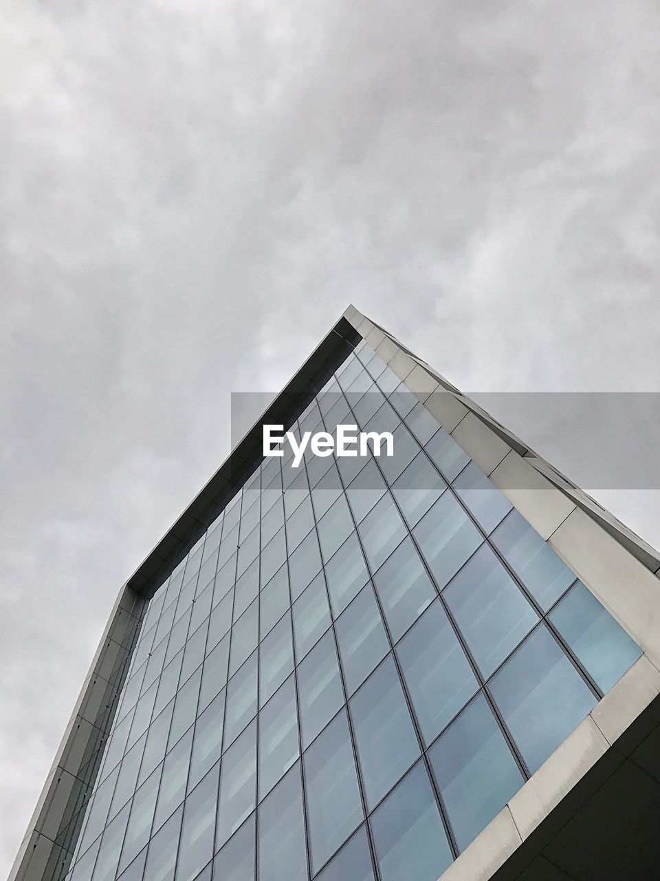 LOW ANGLE VIEW OF GLASS BUILDING AGAINST CLOUDY SKY