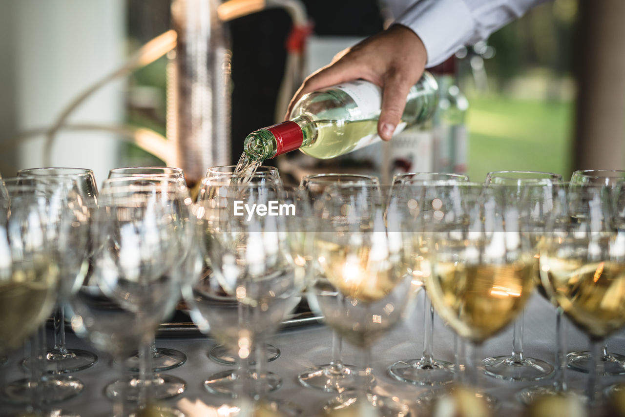 Cropped hand pouring wine in glasses on table