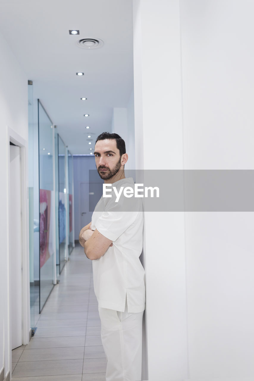 Doctor with arms crossed standing in corridor at hospital