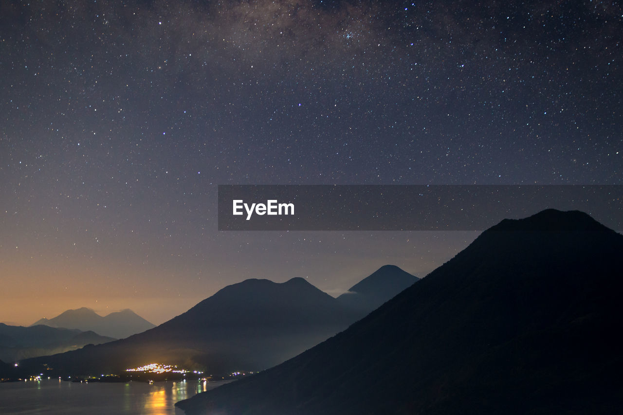 Scenic view of silhouette mountains against star field