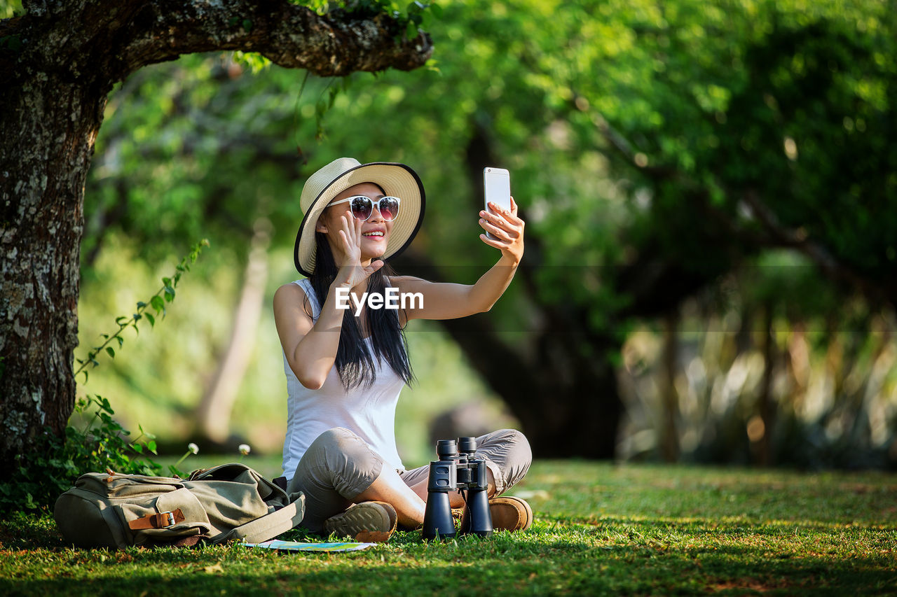Full length of young woman taking selfie from mobile phone on field