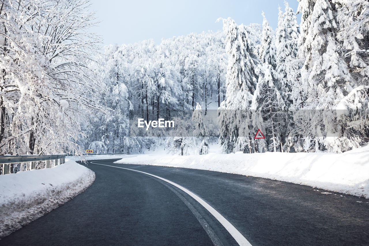 Road amidst snow covered trees 