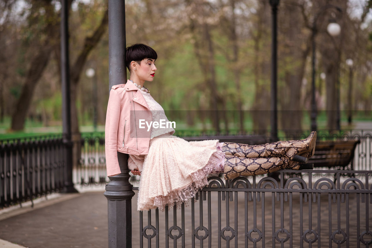 Fashionable woman sitting on railing