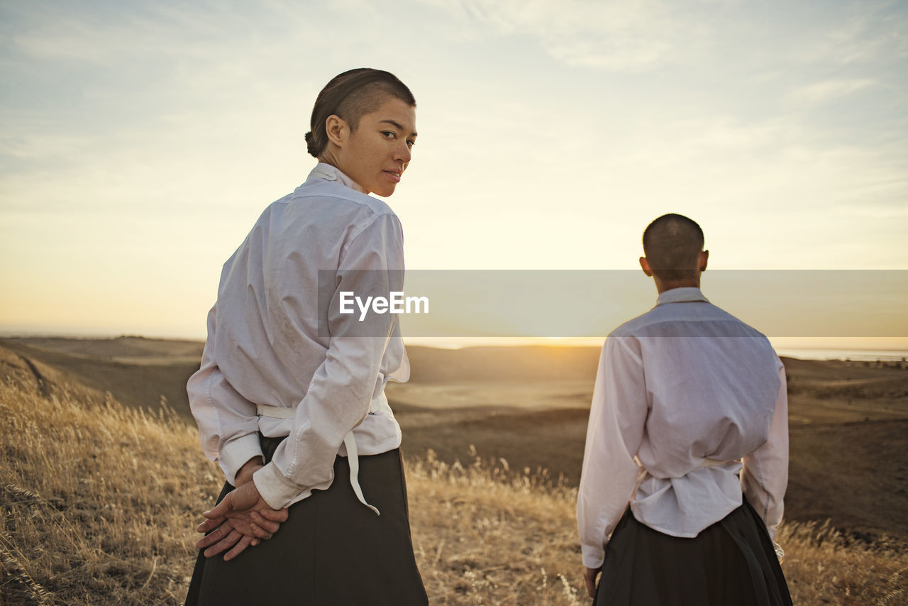 Man and woman standing on field against sky