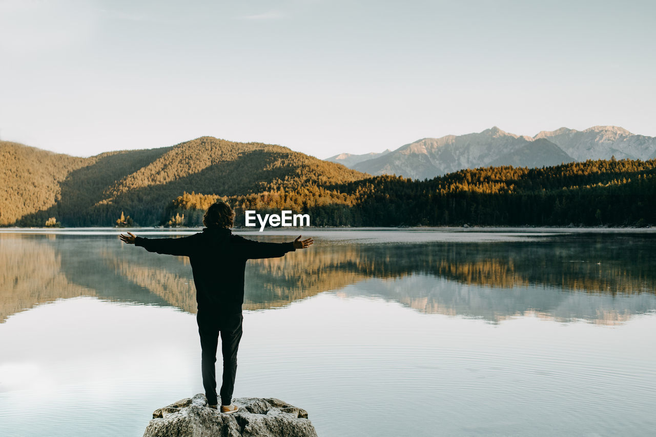 Rear view of woman looking at lake against clear sky