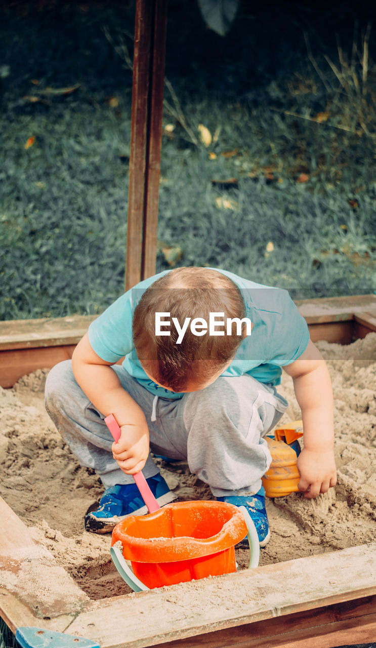 High angle view of boy playing in sandbox