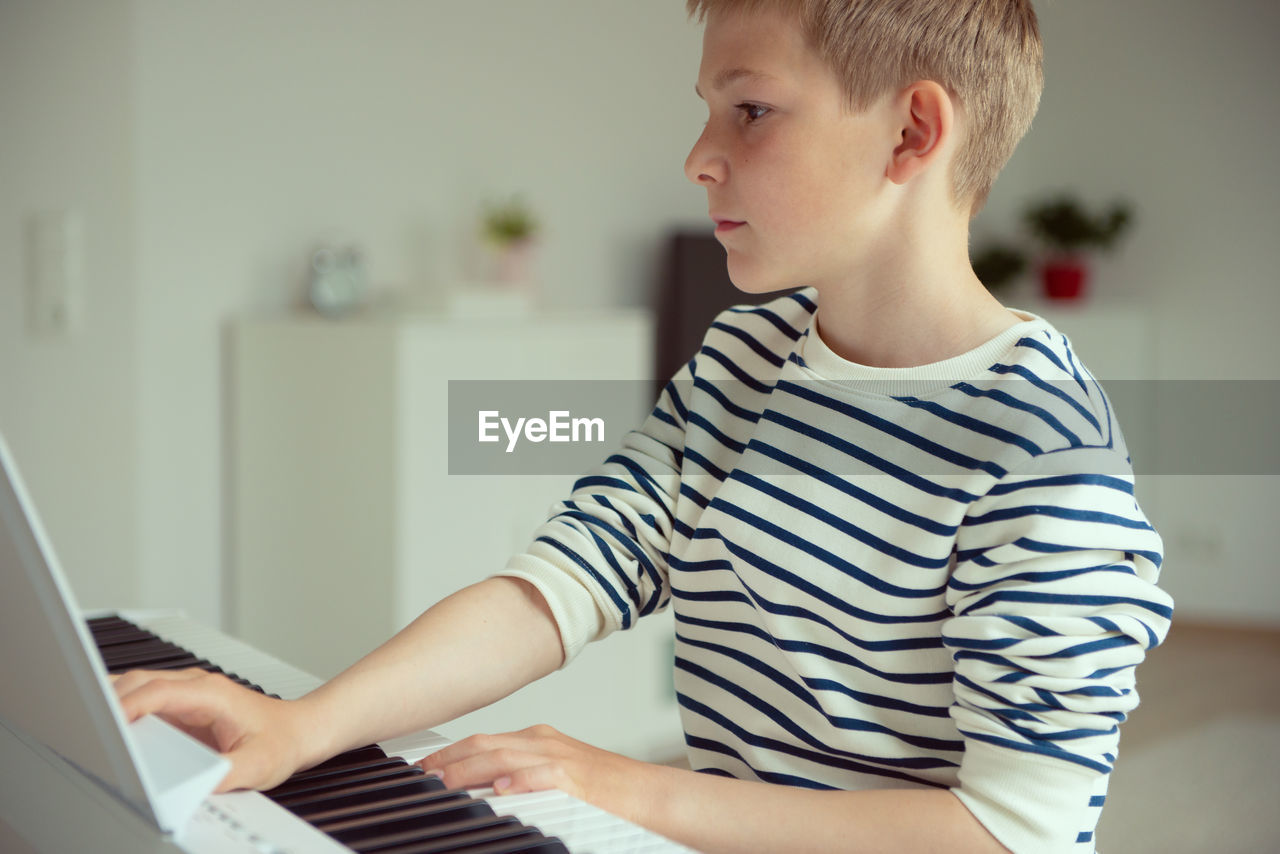 LOW SECTION OF BOY SITTING AT HOME