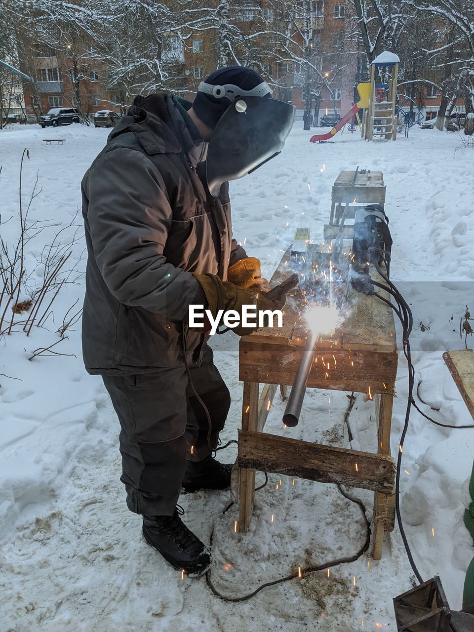 winter, snow, cold temperature, one person, warm clothing, nature, men, adult, freezing, clothing, full length, burning, fire, ice, occupation, tree, protective workwear, protection, flame, blizzard, working, heat, standing, footwear, holding, side view, environment, outdoors, winter storm