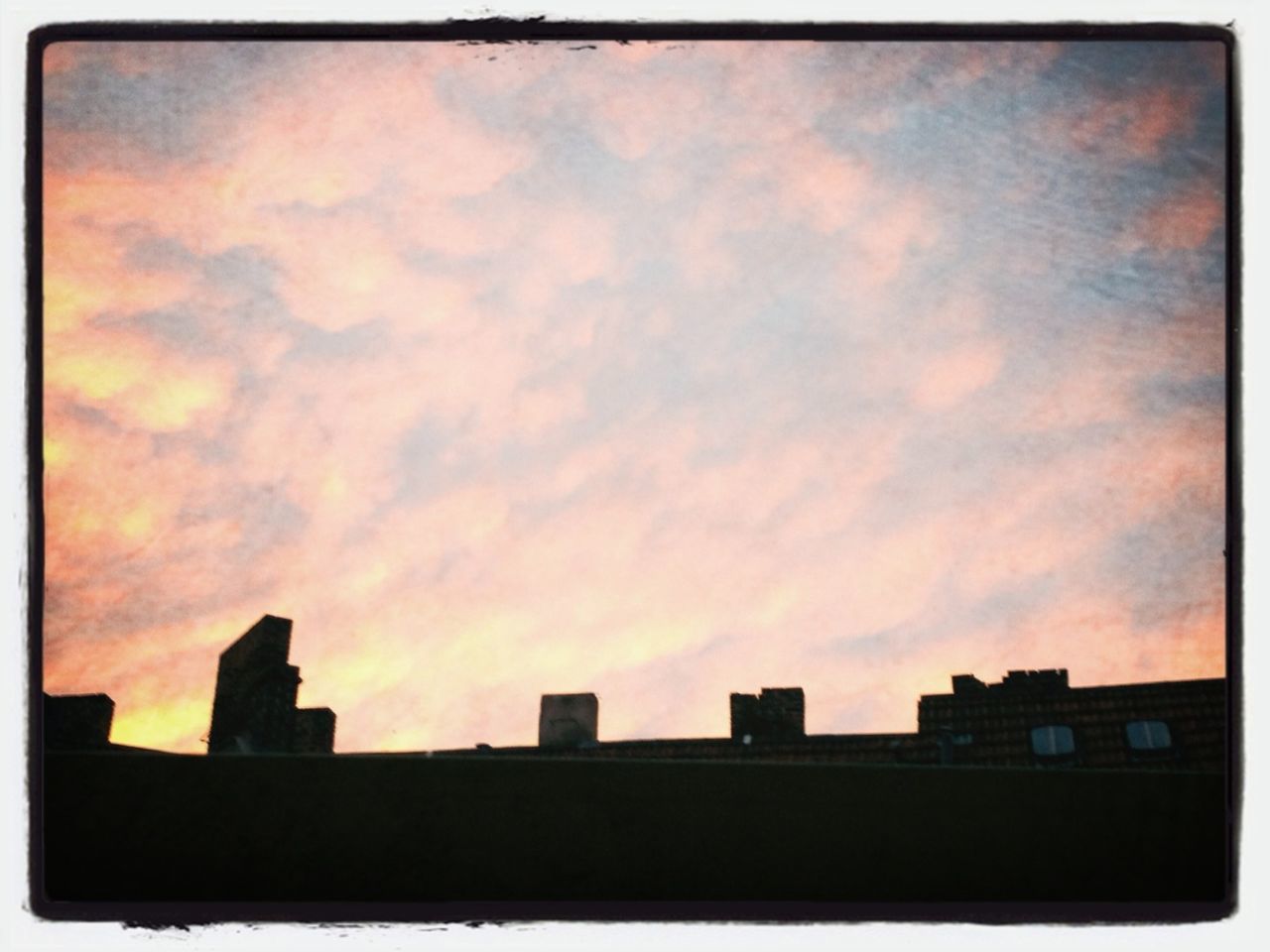 SILHOUETTE OF BUILDINGS AGAINST CLOUDY SKY AT SUNSET