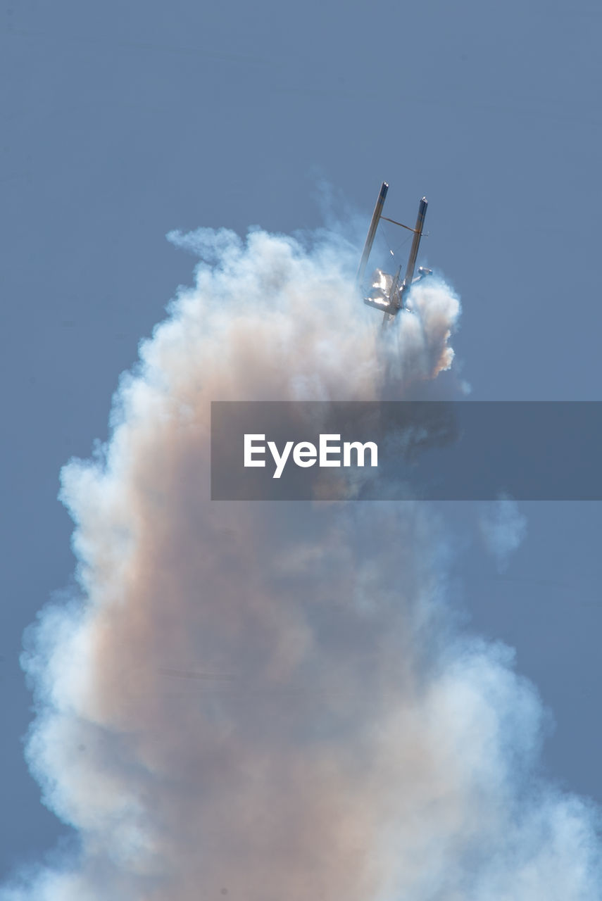 LOW ANGLE VIEW OF AIRSHOW AGAINST VAPOR TRAIL IN SKY